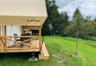 Tienda safari Glampingtent en EuroParcs Veluwemeer, Países Bajos, con terraza de madera y césped verde.