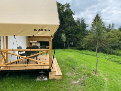 Tente safari Glampingtent à EuroParcs Veluwemeer aux Pays-Bas, terrasse en bois et pelouse verte.