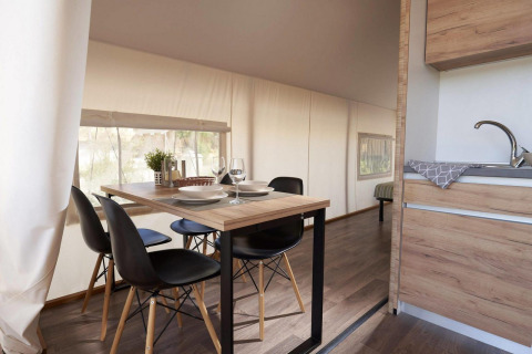 Essbereich mit modernem Holztisch, schwarzen Stühlen in einem Glamping-Zelt mit Küchenzeile.