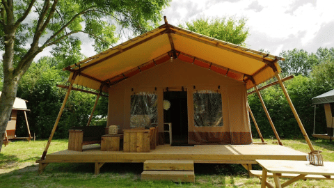 Glampingtent Desert con terraza de madera, muebles exteriores y porche amplio en entorno natural.