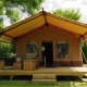 Glampingtent Desert con terraza de madera, muebles exteriores y porche amplio en entorno natural.