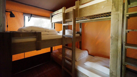 Innenansicht des Glampingtent Desert mit zwei Holz-Etagenbetten und oranger Wand für komfortables Camping.
