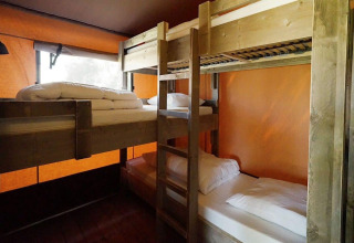 Binnenzicht in Glampingtent Desert met twee houten stapelbedden en oranje muren voor een sfeervol verblijf.