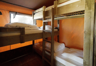 Indvendig udsigt over Glampingtent Desert med to sæt træ køjesenge og orange vægge til hyggelige ophold.