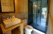 Baño moderno en Glampingtent Desert con lavabo, inodoro y ducha de vidrio, rodeado de decoración de madera.