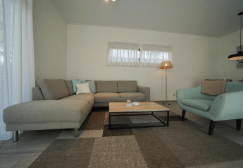 Moderne leefruimte met grijze hoekzetel, blauwe stoel en salontafel in Pavilion bij EuroParcs Veluwemeer, Nederland.