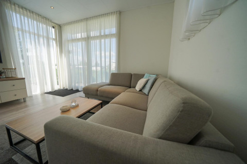 Modernes Wohnzimmer im Pavilion bei EuroParcs Veluwemeer, Niederlande, mit großen Fenstern und Sofa.