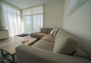 Modernes Wohnzimmer im Pavilion bei EuroParcs Veluwemeer, Niederlande, mit großen Fenstern und Sofa.