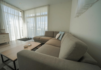 Moderne zithoek in Pavilion bij EuroParcs Veluwemeer, Nederland, met grote ramen en gezellige sofa.