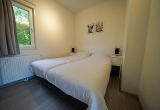 Modernes Schlafzimmer mit zwei Einzelbetten und Fensterblick im Pavilion im EuroParcs Veluwemeer, Niederlande.