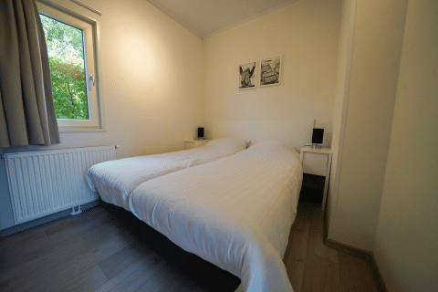 Modernes Schlafzimmer mit zwei Einzelbetten und Fensterblick im Pavilion im EuroParcs Veluwemeer, Niederlande.