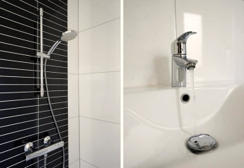 Douche moderne avec mur carrelé noir et blanc et robinetterie, plus lavabo avec robinet dans un lodge.