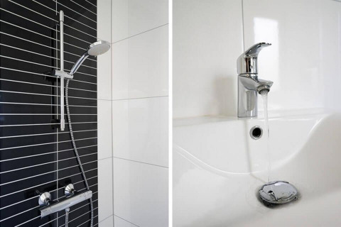 Douche moderne avec mur carrelé noir et blanc et robinetterie, plus lavabo avec robinet dans un lodge.