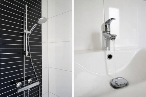 Moderne Dusche mit schwarzer und weißer Fliesenwand und glänzender Armatur sowie Waschbecken im Lodge.