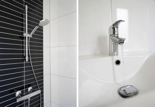 Moderne Dusche mit schwarzer und weißer Fliesenwand und glänzender Armatur sowie Waschbecken im Lodge.