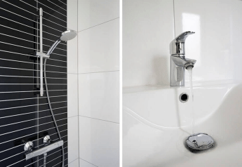 Ducha moderna con pared de azulejos blancos y negros y grifo brillante junto a lavabo en una cabaña.