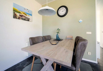 Espace repas moderne dans un lodge avec table en bois, chaises rembourrées et décoration murale élégante.