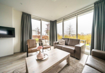 Helles, modernes Wohnzimmer einer Lodge im EuroParcs Veluwemeer, Niederlande, mit großen Fenstern und stilvollem Mobiliar.