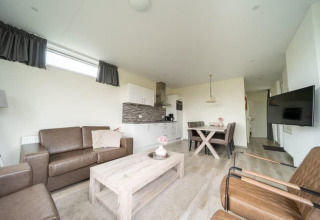 Heldere, moderne woonkamer met keuken en eetgedeelte in het Pavilion lodge bij EuroParcs Veluwemeer, Nederland.