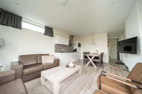 Soggiorno luminoso e moderno con cucina e zona pranzo nel Pavilion lodge di EuroParcs Veluwemeer, Olanda.