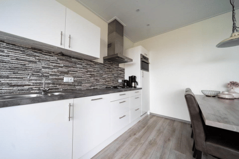 Moderne køkken og spisestue i lodge ved Pavilion på EuroParcs Veluwemeer, Holland, med grå detaljer.