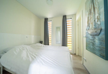 Helles Schlafzimmer mit zwei Einzelbetten, Gemälde und großen Fenstern im Pavilion bei EuroParcs Veluwemeer.