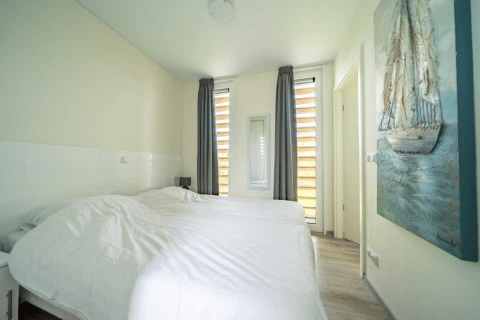 Helles Schlafzimmer mit zwei Einzelbetten, Gemälde und großen Fenstern im Pavilion bei EuroParcs Veluwemeer.