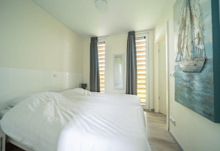 Helles Schlafzimmer mit zwei Einzelbetten, Gemälde und großen Fenstern im Pavilion bei EuroParcs Veluwemeer.