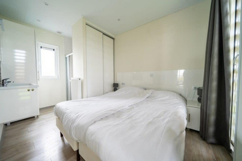 Helles Schlafzimmer im Pavilion bei EuroParcs Veluwemeer, Niederlande, mit Doppelbett und großem Schrank.