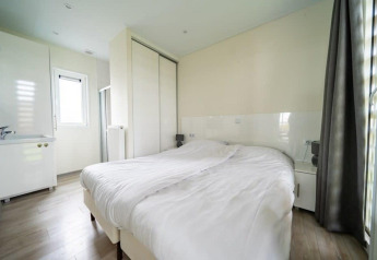 Helles Schlafzimmer im Pavilion bei EuroParcs Veluwemeer, Niederlande, mit Doppelbett und großem Schrank.