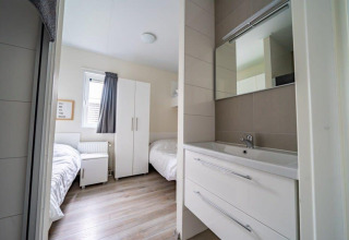 Chambre moderne au Pavilion d’EuroParcs Veluwemeer, Pays-Bas, lits jumeaux et lavabo contemporain.