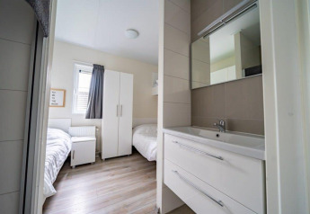 Modernes Lodge-Zimmer im Pavilion bei EuroParcs Veluwemeer, Niederlande, mit zwei Betten und Waschbecken.