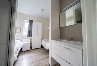 Camera moderna al Pavilion, EuroParcs Veluwemeer nei Paesi Bassi, con letti singoli e lavabo moderno.