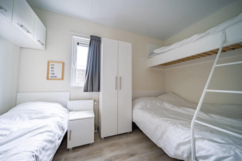 Habitación luminosa con litera, cama individual, armario y cartel en Pavilion de EuroParcs Veluwemeer, Países Bajos.