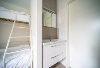 Habitación moderna del lodge Pavilion en EuroParcs Veluwemeer, Holanda, con litera y lavabo blanco.