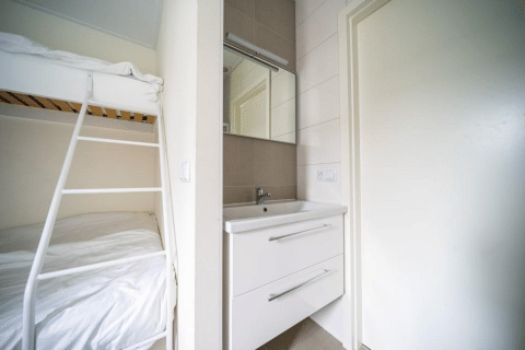 Camera moderna al Pavilion di EuroParcs Veluwemeer, Paesi Bassi, con letto a castello e lavabo bianco.