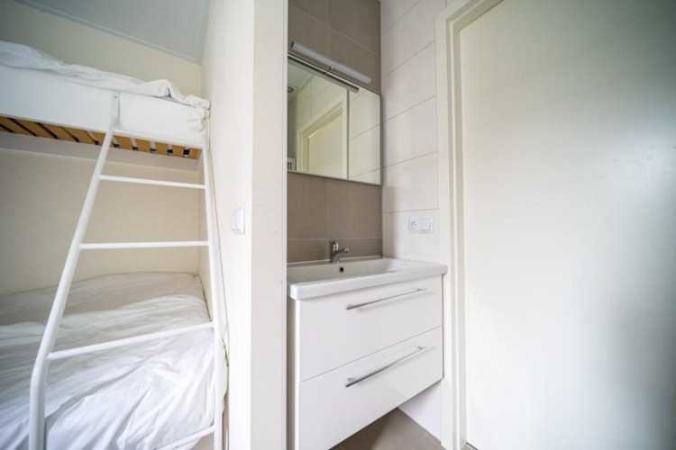 Habitación moderna del lodge Pavilion en EuroParcs Veluwemeer, Holanda, con litera y lavabo blanco.