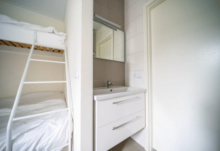 Modernes Lodge-Zimmer im Pavilion bei EuroParcs Veluwemeer, Niederlande, mit Etagenbett und Waschbecken.