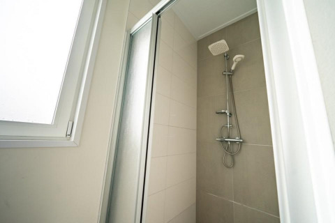 Ducha moderna con puerta de vidrio y ventana en el Pavilion de EuroParcs Veluwemeer, Países Bajos.