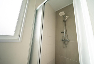 Ducha moderna con puerta de vidrio y ventana en el Pavilion de EuroParcs Veluwemeer, Países Bajos.