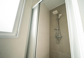 Cabine de douche moderne avec porte vitrée et fenêtre au Pavilion d’EuroParcs Veluwemeer aux Pays-Bas.