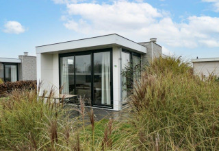 Lodge Pavilion moderno con grandes ventanales rodeado de césped en EuroParcs Veluwemeer, Países Bajos.