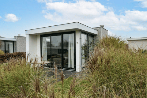 Lodge Pavilion moderno con grandes ventanales rodeado de césped en EuroParcs Veluwemeer, Países Bajos.