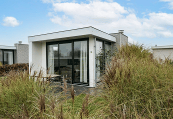 Moderne Pavilion-lodge met grote ramen tussen het gras bij EuroParcs Veluwemeer in Nederland.