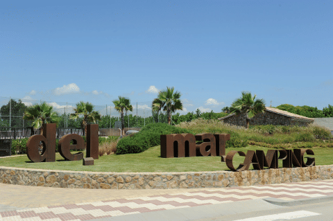 Eingang des Camping del Mar Ferienparks in Katalonien, Spanien mit Palmen und großen Buchstaben bei Sonne.