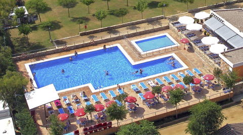 Vista aérea de piscina, tumbonas y sombrillas en el Camping del Mar, parque vacacional en Cataluña, España.