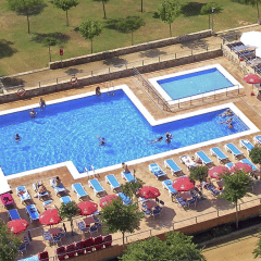 Vista aérea de piscina, tumbonas y sombrillas en el Camping del Mar, parque vacacional en Cataluña, España.