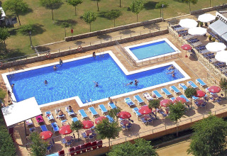 Vue aérienne de la piscine avec transats et parasols au Camping del Mar, parc de vacances en Catalogne, Espagne.