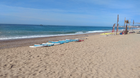 Photo de la plage au Camping del Mar en Catalogne, Espagne, avec des planches de surf sur le sable.