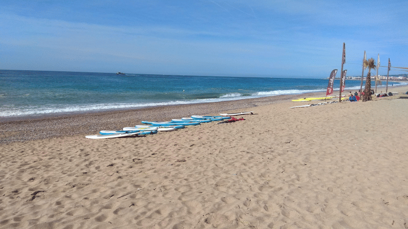 Photo de la plage au Camping del Mar en Catalogne, Espagne, avec des planches de surf sur le sable.